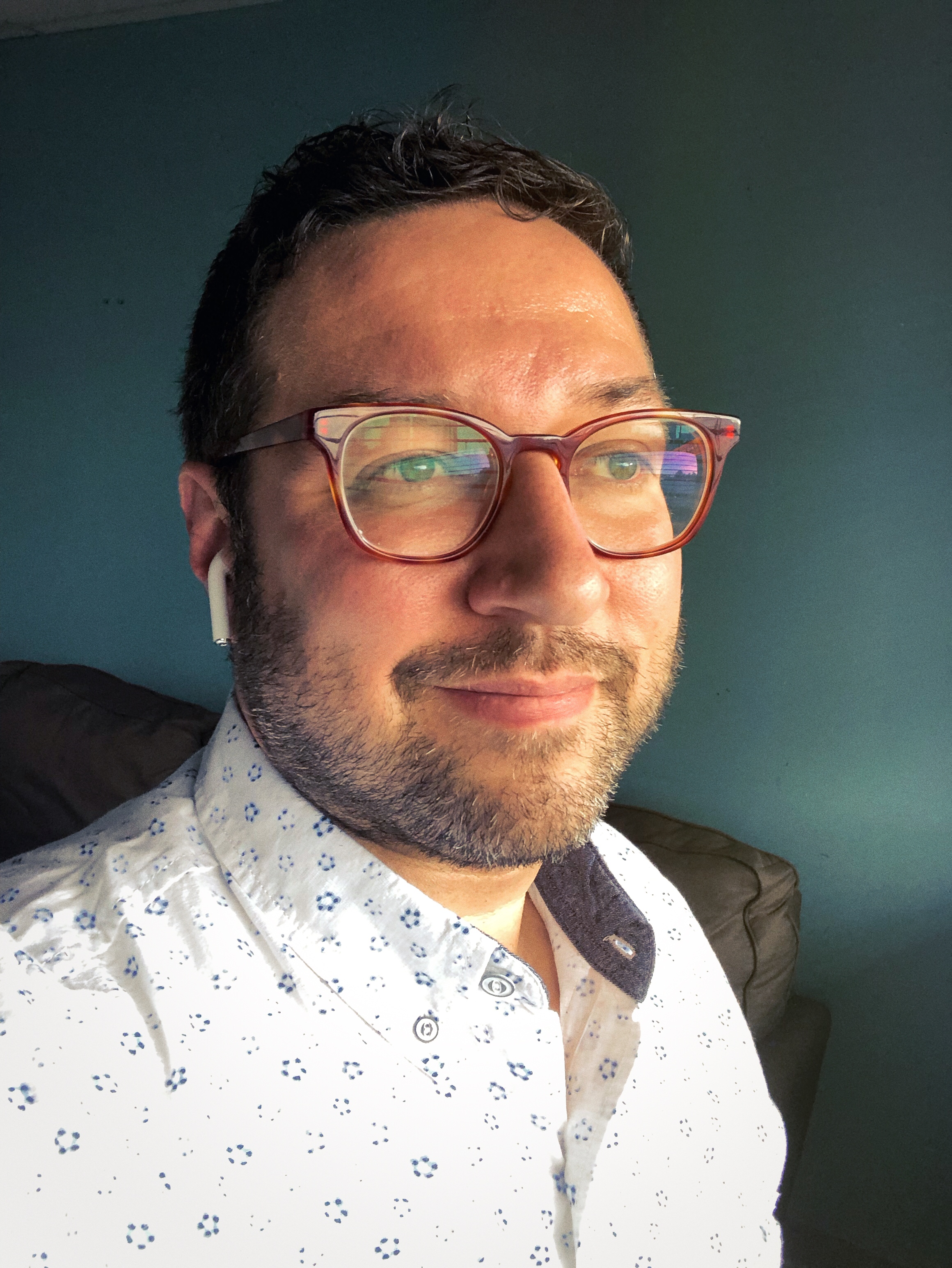 Jonathan Castillo in burgundy glasses and a patterned shirt